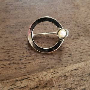 Gold circle brooch with pearl in heart.